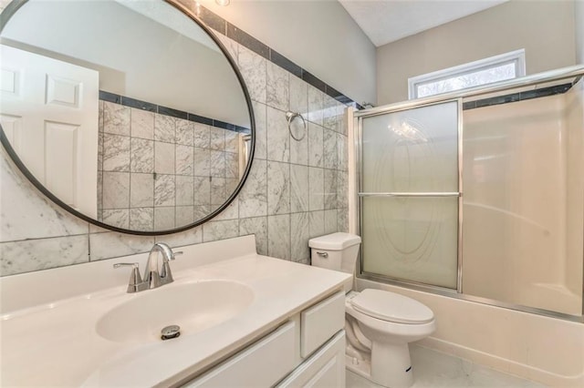 full bathroom featuring tile walls, enclosed tub / shower combo, vanity, and toilet