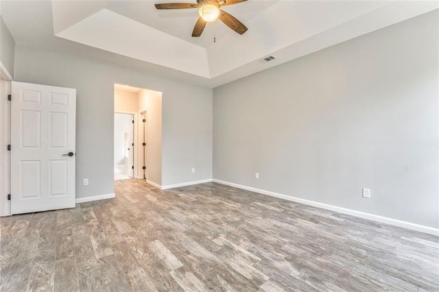 unfurnished bedroom featuring ceiling fan, hardwood / wood-style flooring, and a tray ceiling