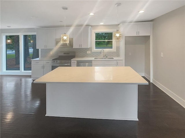 kitchen featuring stainless steel appliances, pendant lighting, plenty of natural light, sink, and white cabinetry