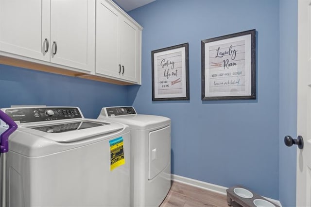 washroom with independent washer and dryer, light hardwood / wood-style floors, and cabinets