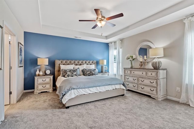 bedroom with light carpet, a raised ceiling, and ceiling fan