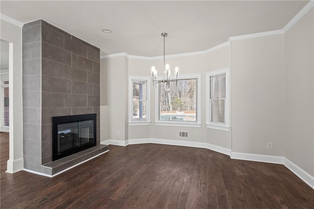 unfurnished living room featuring a tile fireplace, dark wood-type flooring, a notable chandelier, and ornamental molding