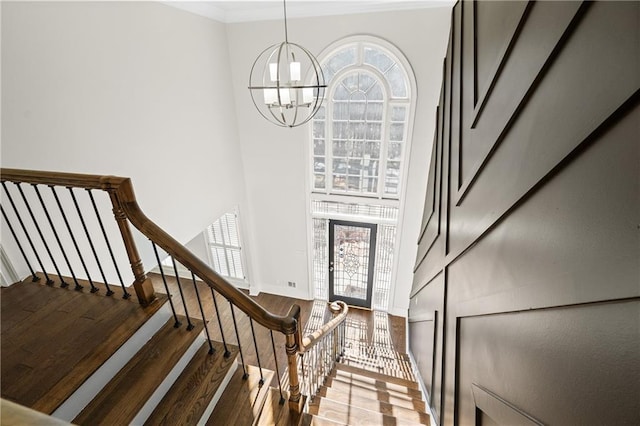 staircase featuring an inviting chandelier, wood-type flooring, and a wealth of natural light