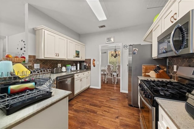 858 Red Rock Ct, Suwanee, GA 30024 - kitchen with appliances with stainless steel finishes, dark wood-type flooring, white cabinetry, decorative backsplash, and light stone countertops