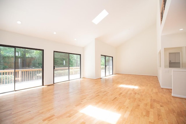 spare room with high vaulted ceiling, light hardwood / wood-style floors, and a skylight