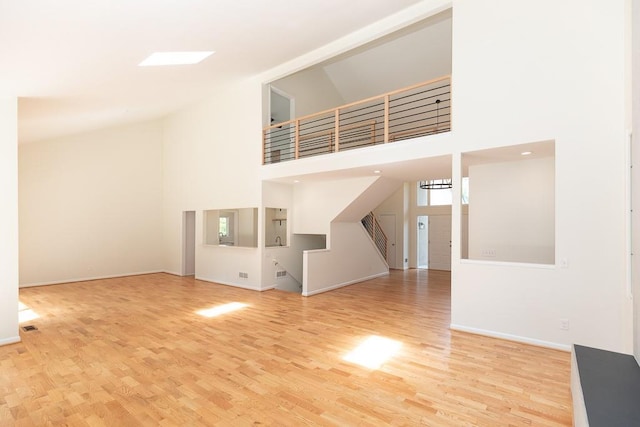 unfurnished living room featuring light hardwood / wood-style floors and a towering ceiling