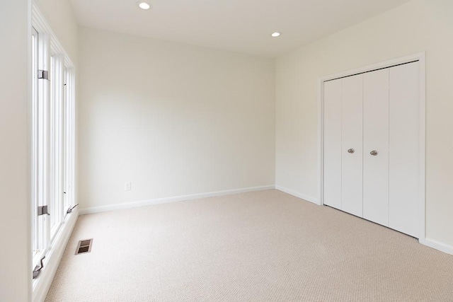 unfurnished bedroom with a closet and light colored carpet