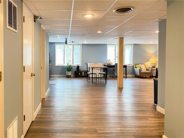 interior space with ceiling fan, a drop ceiling, and wood-type flooring