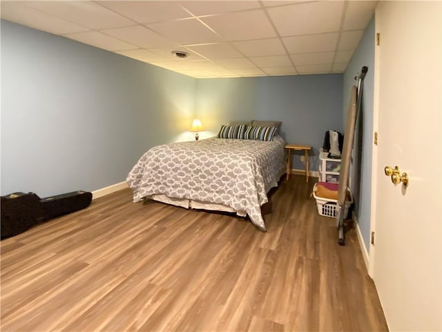 bedroom with a drop ceiling and hardwood / wood-style floors