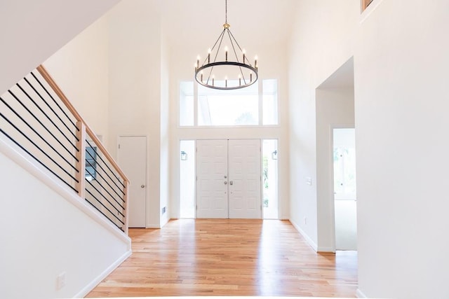 foyer entrance featuring light hardwood / wood-style floors, a notable chandelier, and a high ceiling