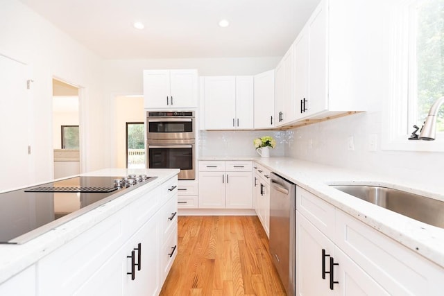 kitchen with white cabinetry, light hardwood / wood-style floors, a healthy amount of sunlight, and appliances with stainless steel finishes