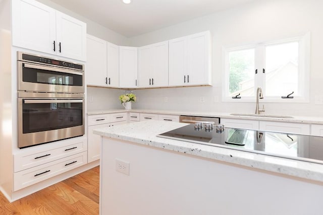 kitchen featuring light stone counters, sink, appliances with stainless steel finishes, and light wood-type flooring