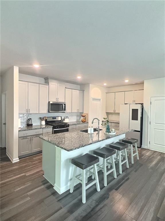 283 Wells Cir, Canton, GA 30114 - kitchen featuring stainless steel appliances, a sink, dark wood-type flooring, an island with sink, and a kitchen breakfast bar
