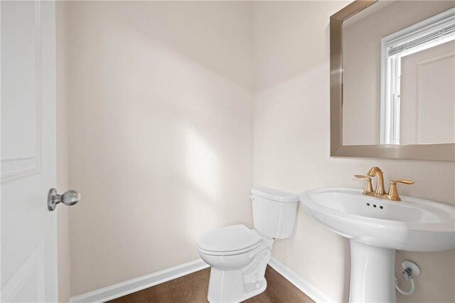 bathroom with a sink, wood finished floors, toilet, and baseboards