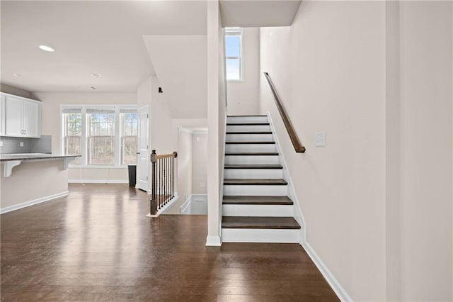 staircase with baseboards, wood finished floors, and recessed lighting