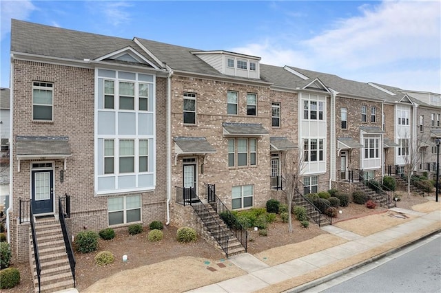 townhome / multi-family property with stairs and brick siding