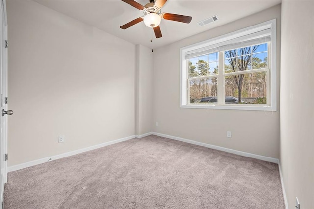 spare room featuring a ceiling fan, visible vents, light carpet, and baseboards