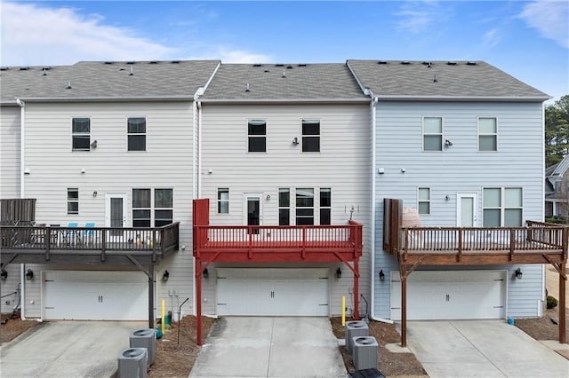 rear view of property featuring central AC, driveway, and an attached garage