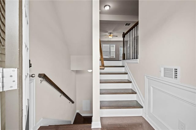 stairway featuring a ceiling fan, baseboards, visible vents, and wood finished floors