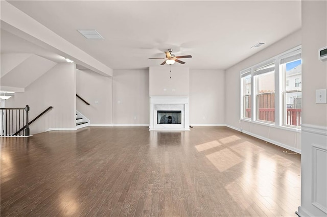 unfurnished living room featuring a fireplace, wood finished floors, a ceiling fan, baseboards, and stairway