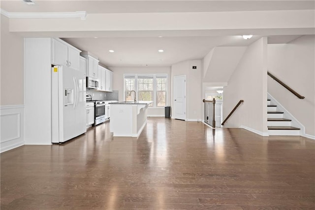 kitchen with white cabinetry, open floor plan, light countertops, appliances with stainless steel finishes, and a center island with sink