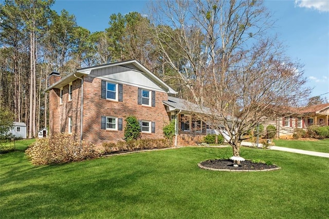 view of front facade featuring brick siding, a chimney, and a front lawn