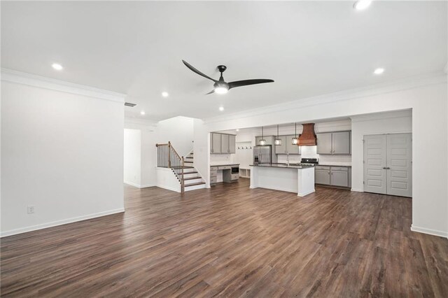 unfurnished living room with ceiling fan, a large fireplace, dark hardwood / wood-style flooring, and ornamental molding