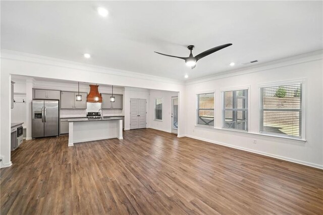 unfurnished living room featuring dark wood-type flooring, ceiling fan, and ornamental molding