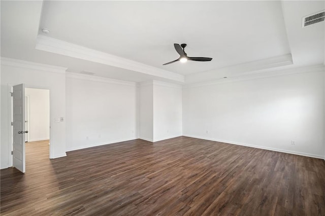 spare room featuring ceiling fan, dark hardwood / wood-style flooring, ornamental molding, and a tray ceiling