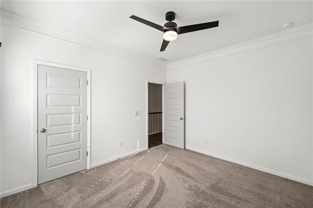 empty room with ceiling fan, carpet floors, and crown molding