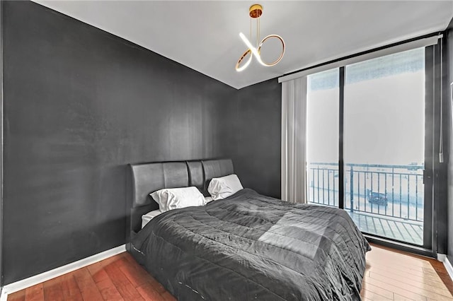 bedroom with hardwood / wood-style flooring, a water view, access to outside, and expansive windows