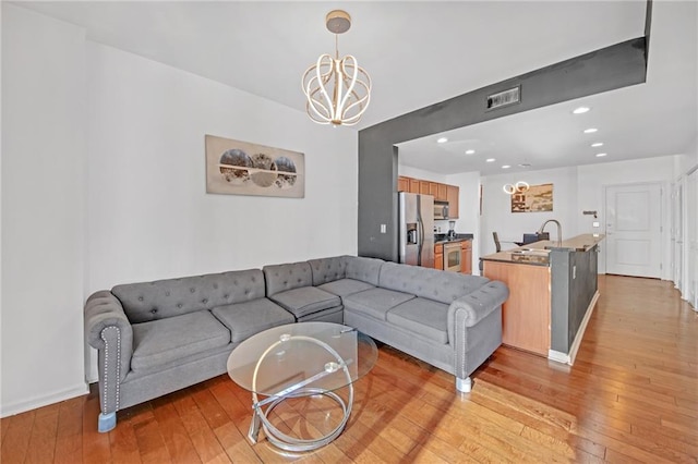 living room featuring sink, an inviting chandelier, and light hardwood / wood-style floors