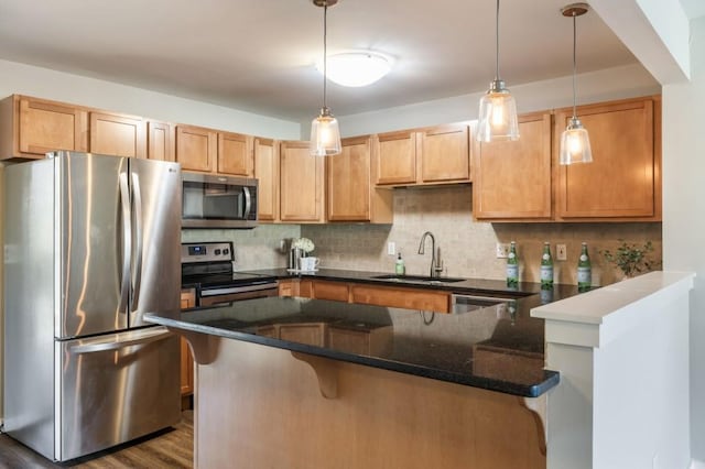 kitchen with stainless steel appliances, a peninsula, a sink, decorative backsplash, and a kitchen bar