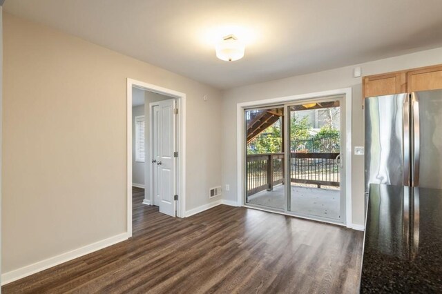 spare room featuring baseboards and dark wood finished floors