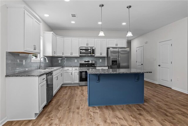 kitchen with sink, a kitchen island, appliances with stainless steel finishes, and white cabinets