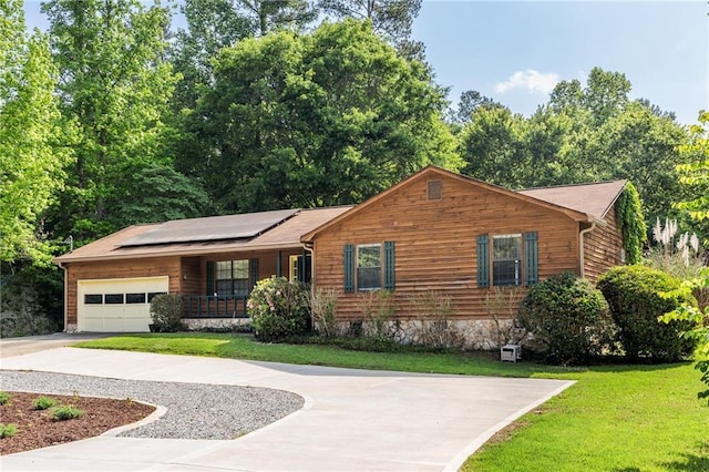 view of front facade featuring a porch, an attached garage, concrete driveway, roof mounted solar panels, and a front lawn