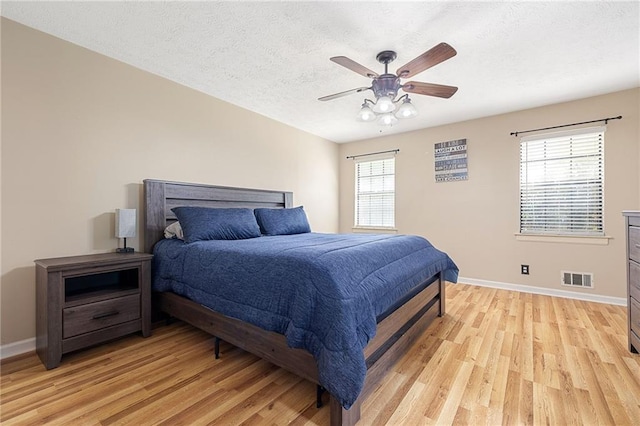 bedroom with multiple windows, baseboards, visible vents, and light wood-style floors