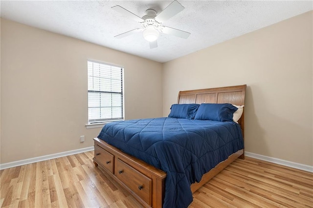 bedroom featuring light wood finished floors, a textured ceiling, baseboards, and ceiling fan