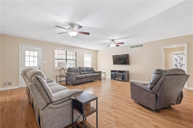 living room featuring a ceiling fan, visible vents, and a textured ceiling