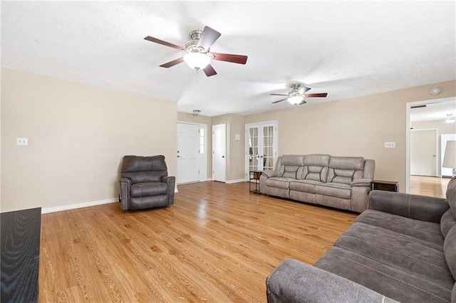 living area featuring light wood finished floors, baseboards, french doors, and a ceiling fan