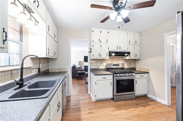 kitchen featuring a sink, under cabinet range hood, ceiling fan, decorative backsplash, and appliances with stainless steel finishes