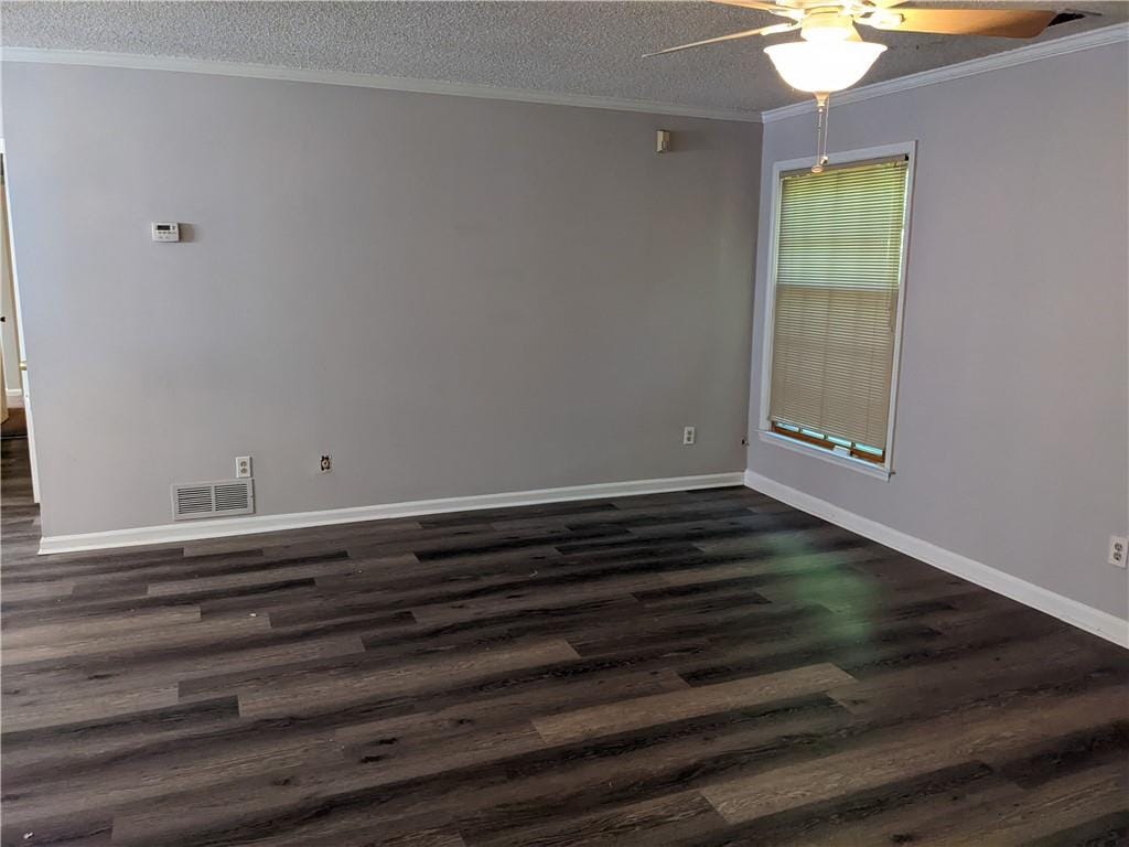 empty room with ceiling fan, dark wood-type flooring, a textured ceiling, and ornamental molding