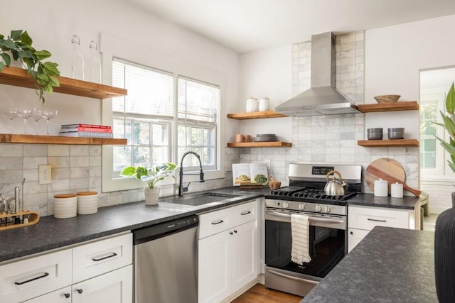 kitchen featuring decorative backsplash, wall chimney exhaust hood, stainless steel appliances, sink, and white cabinetry