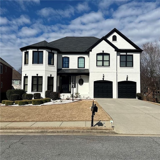 view of front of house with a garage, driveway, and a shingled roof