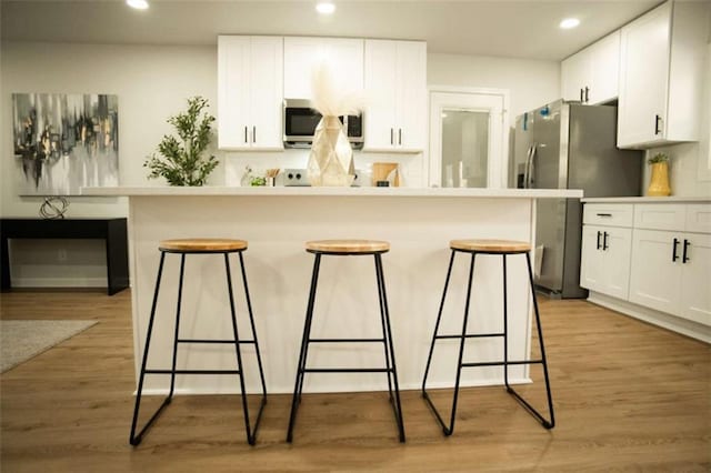 kitchen featuring light hardwood / wood-style floors, a breakfast bar, and white cabinets