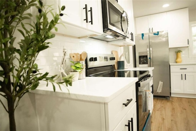 kitchen with tasteful backsplash, white cabinets, light wood-type flooring, and stainless steel appliances