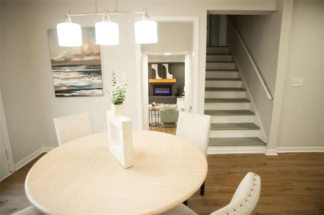 dining room with dark wood-type flooring and a large fireplace