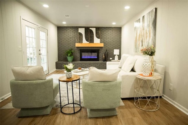 living room with a brick fireplace, hardwood / wood-style flooring, and french doors