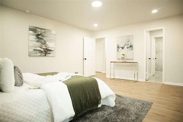 bedroom with connected bathroom and hardwood / wood-style floors