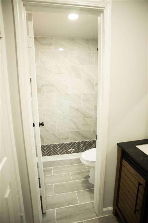 bathroom featuring toilet, vanity, and a tile shower